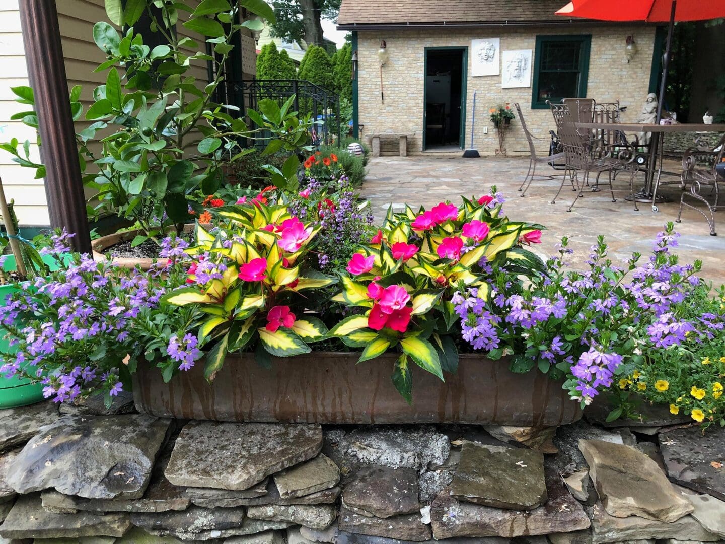 Stone wall with a planter filled with colorful flowers sitting on top of it