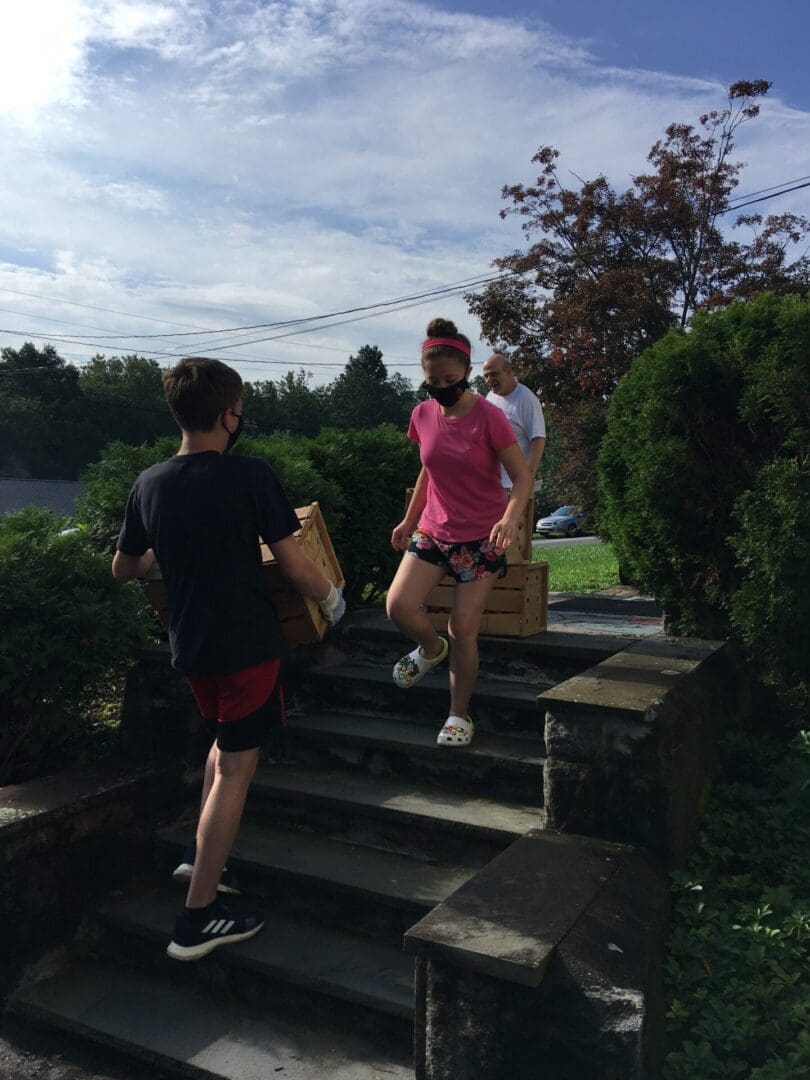 Man and woman walking up some steps with boxes in their hands